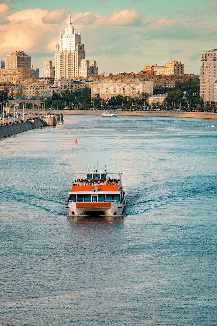 A ferry boat cruising on Moscow River with iconic city view on a clear day.