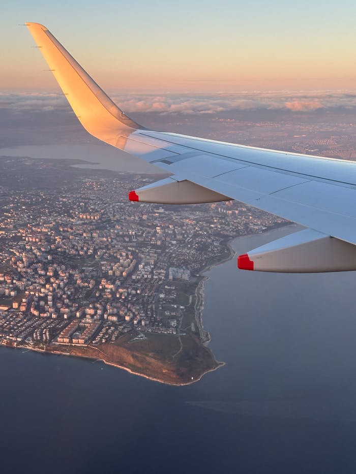 Sunset aerial view of Istanbul city from airplane wing, serene sky and landscape.