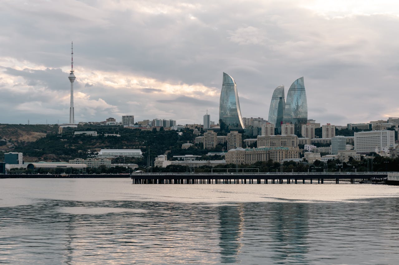 Scenic view of Baku skyline with Flame Towers and Caspian Sea in the foreground.